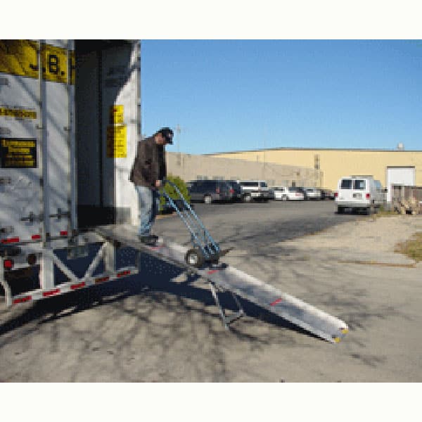 Man using a Portable Delivery Ramp 750lb W/ Mounting Brackets with a dolly or hand truck to unload a semi truck trailer container