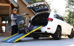 Person loading scooter into vehicle using a portable wheelchair ramp